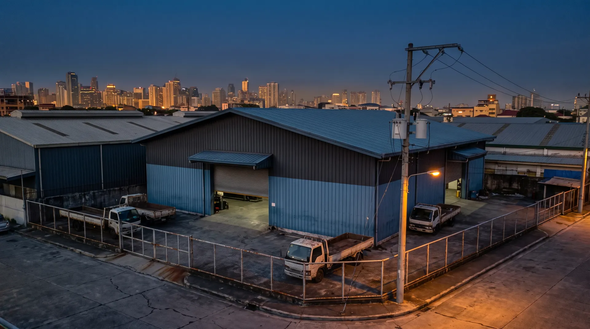 A Philippine metal-fabrication building at dusk, city skyline behind it